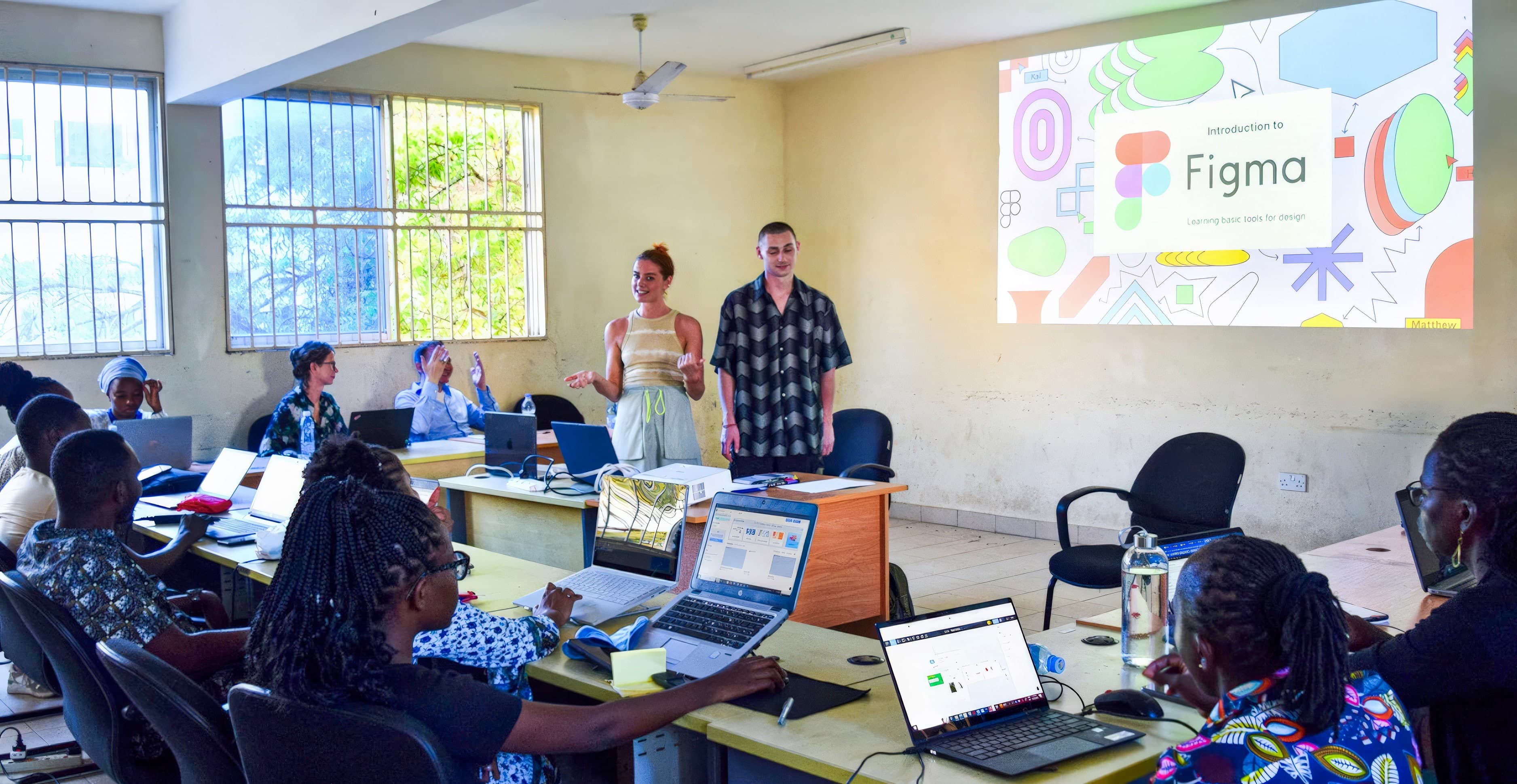 Olivia and Lukas discussing a Figma tutorial with students in a classroom at Pwani University, Kilifi, Kenya